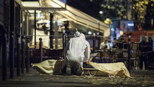 Des policiers français recouvrent une victime des attentats de Paris, le 13 novembre 2015. Crédits: MAXPPP
