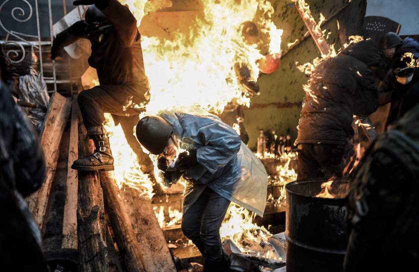 Protesters burn as they stand behind burning barricades during clashes with police on February 20, 2014 in Kiev. Ukraine's embattled leader announced a "truce" with the opposition as he prepared to get grilled by visiting EU diplomats over clashes that killed 26 and left the government facing diplomatic isolation. The shocking scale of the violence three months into the crisis brought expressions of grave concern from the West and condemnation of an "attempted coup" by the Kremlin.   AFP PHOTO/BULENT KILICBULENT KILIC/AFP/Getty Images